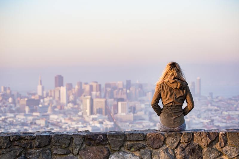 Woman sitting on ledge overlooking city