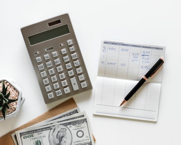 A calculator and pad of paper with numbers written on it