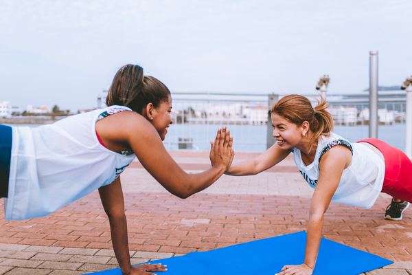 two women doing a one-armed plank and high-fiving