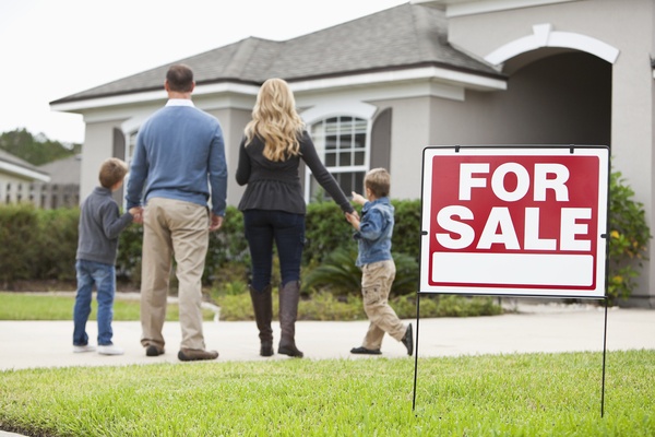 Family standing by home for sale sign