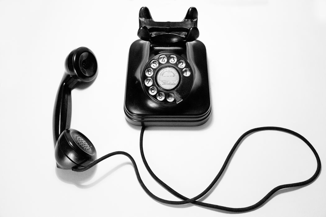 Black rotary phone on a white background.